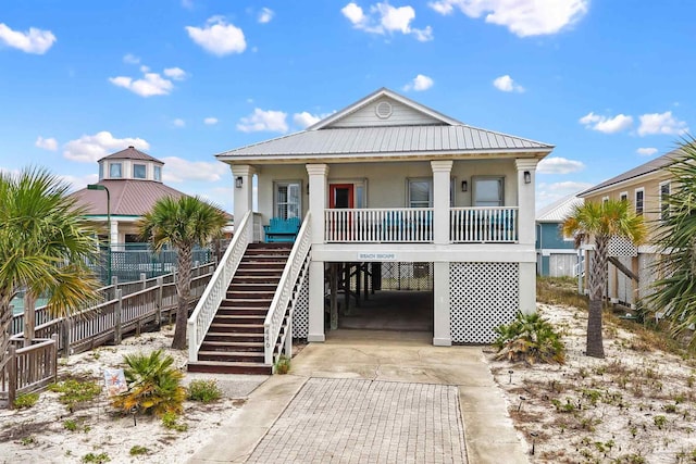 446 Harbor Light Cir, Gulf Shores, AL 36542 - coastal home featuring a carport, concrete driveway, a porch, stucco siding, and metal roof