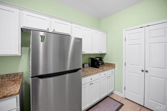 446 Harbor Light Cir, Gulf Shores, AL 36542 - kitchen with freestanding refrigerator, white cabinets, stone counters, and light tile patterned floors