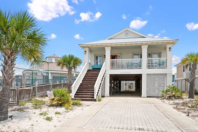446 Harbor Light Cir, Gulf Shores, AL 36542 - raised beach house featuring a carport, covered porch, stucco siding, fence, and concrete driveway