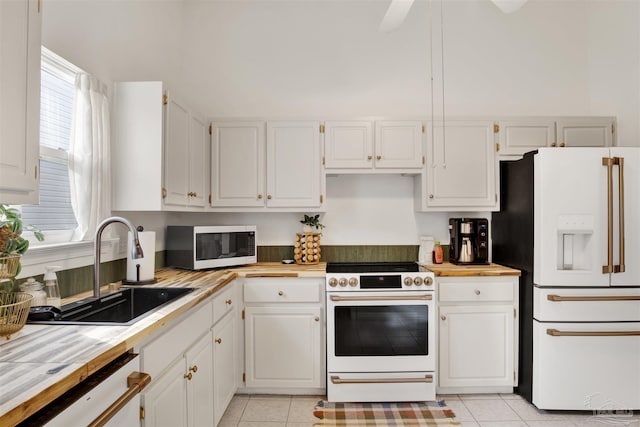 kitchen with light tile patterned flooring, white appliances, white cabinetry, and sink