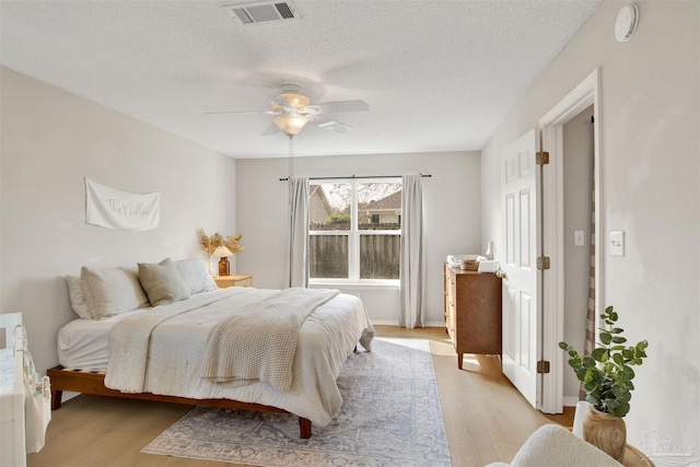 bedroom featuring ceiling fan, light wood-type flooring, and a textured ceiling