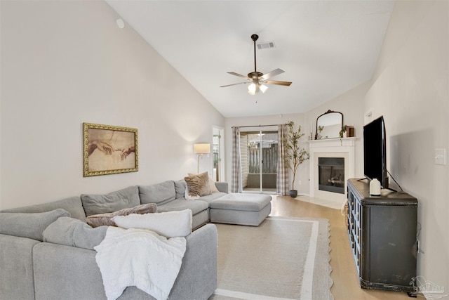 living room with ceiling fan, light wood-type flooring, and high vaulted ceiling