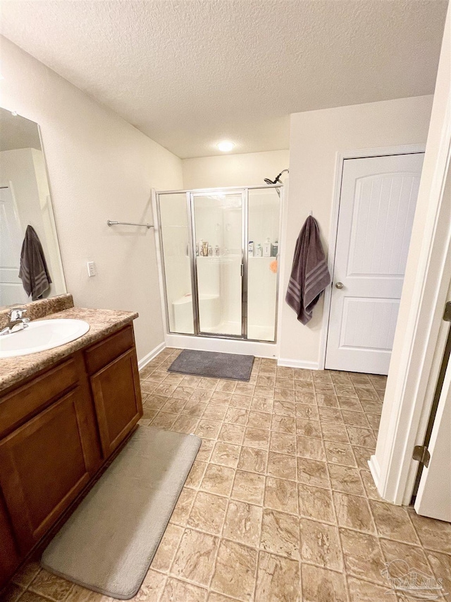 bathroom with a textured ceiling, vanity, and an enclosed shower