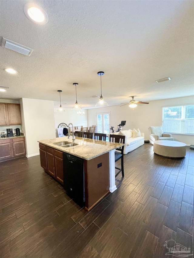 kitchen with ceiling fan, sink, decorative light fixtures, a center island with sink, and black dishwasher