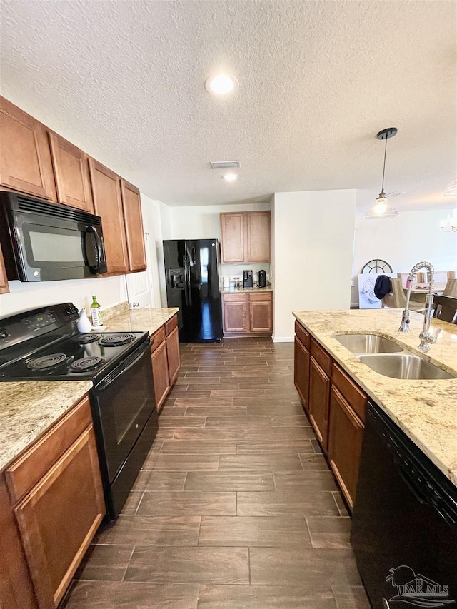 kitchen featuring light stone countertops, sink, pendant lighting, a textured ceiling, and black appliances