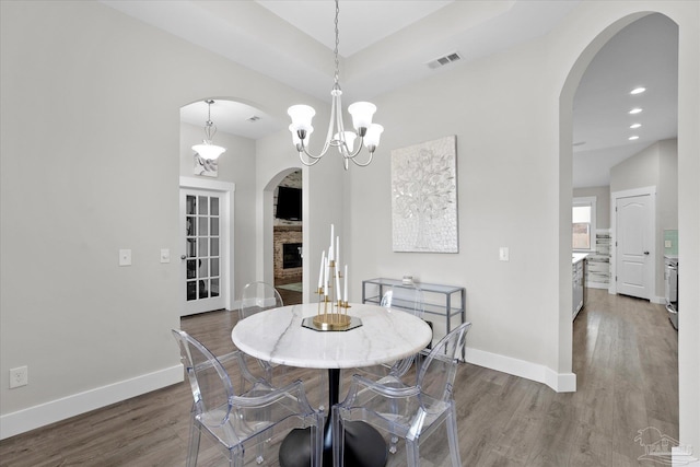 dining room featuring hardwood / wood-style floors, a notable chandelier, and a fireplace