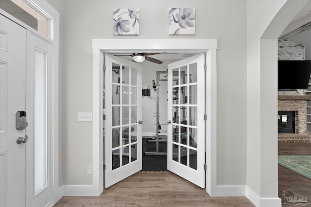 entryway with hardwood / wood-style flooring, ceiling fan, and a fireplace