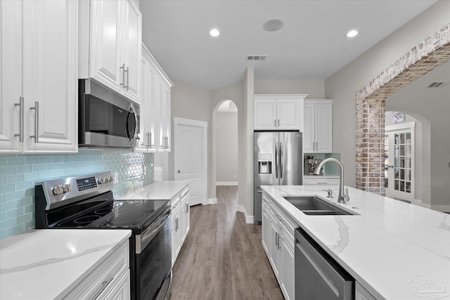 kitchen featuring stainless steel appliances, white cabinetry, sink, and light stone counters