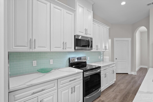 kitchen featuring light hardwood / wood-style flooring, stainless steel appliances, light stone counters, tasteful backsplash, and white cabinets