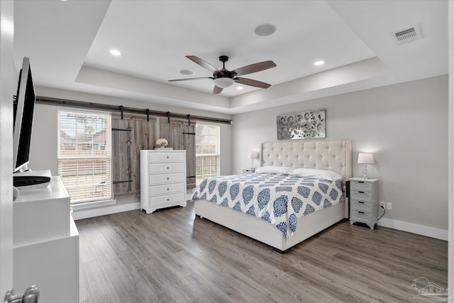 bedroom featuring ceiling fan, a tray ceiling, and hardwood / wood-style floors