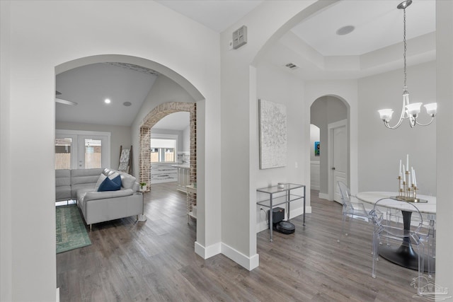 corridor featuring hardwood / wood-style flooring, a towering ceiling, and a chandelier