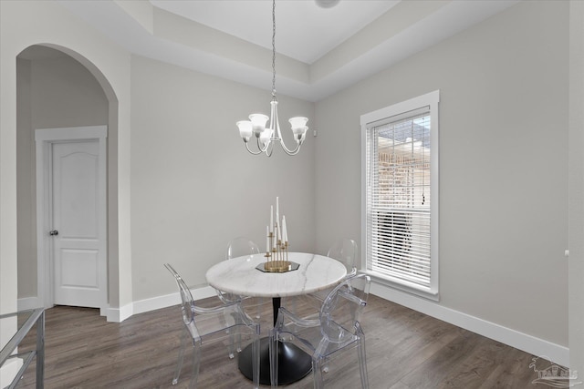 dining area with dark wood-type flooring and a notable chandelier