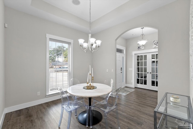 dining room with an inviting chandelier, dark hardwood / wood-style floors, and a raised ceiling