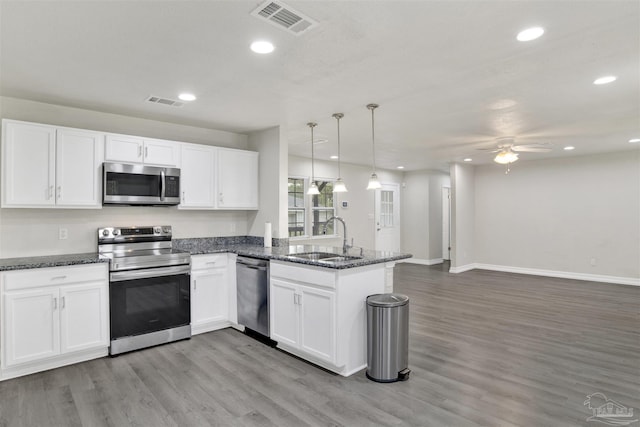 kitchen featuring white cabinets, hanging light fixtures, sink, appliances with stainless steel finishes, and kitchen peninsula