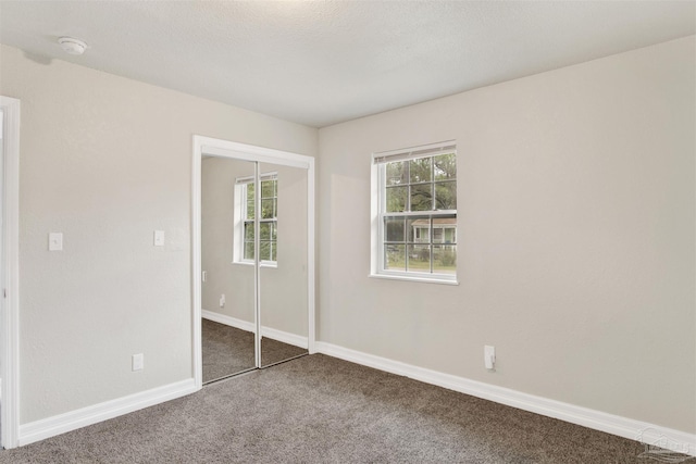 unfurnished bedroom featuring carpet flooring, a closet, and a textured ceiling