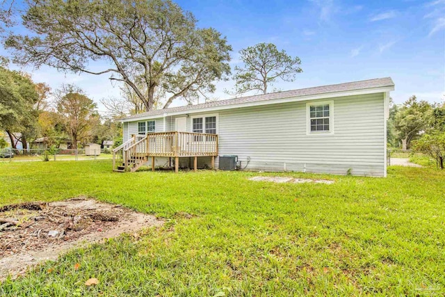 rear view of property with central air condition unit, a wooden deck, and a lawn