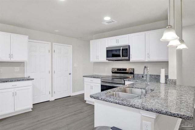 kitchen featuring kitchen peninsula, pendant lighting, stainless steel appliances, and white cabinets