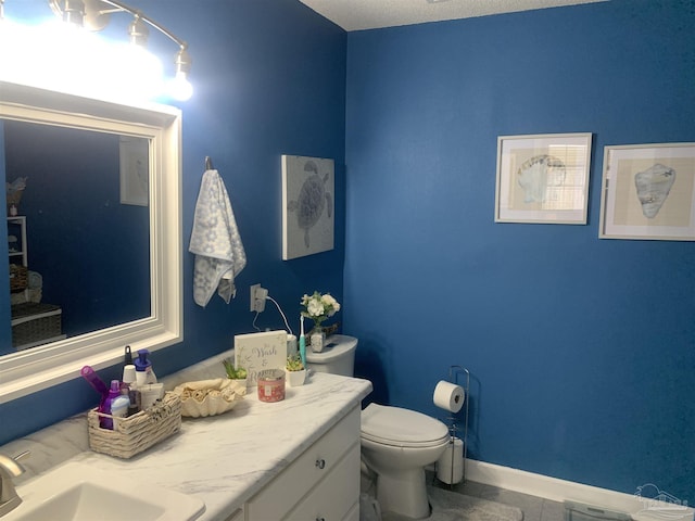 bathroom featuring tile patterned flooring, toilet, vanity, and baseboards