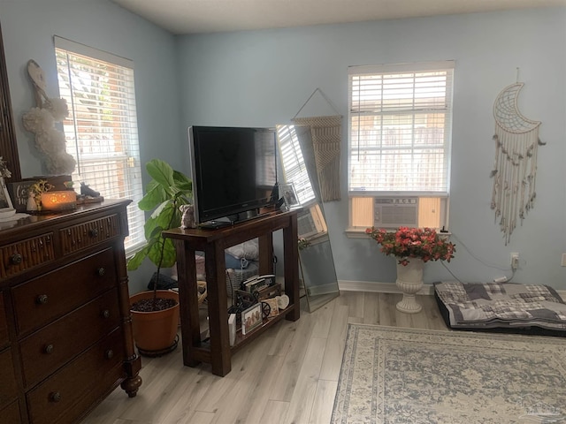 living area featuring plenty of natural light, light wood-style flooring, and cooling unit