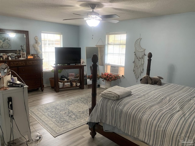 bedroom featuring ceiling fan, cooling unit, wood finished floors, and a textured ceiling