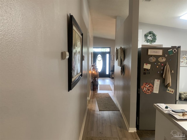 corridor featuring baseboards and wood finished floors