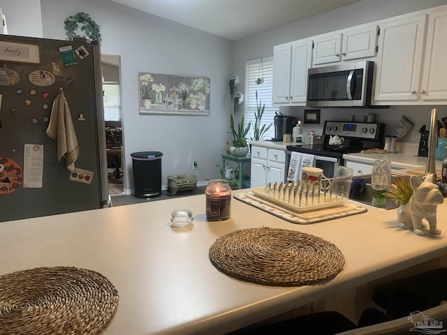 kitchen with light countertops, white cabinets, vaulted ceiling, and stainless steel appliances