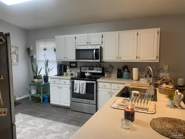 kitchen featuring light countertops, white cabinets, dark tile patterned floors, and stainless steel appliances