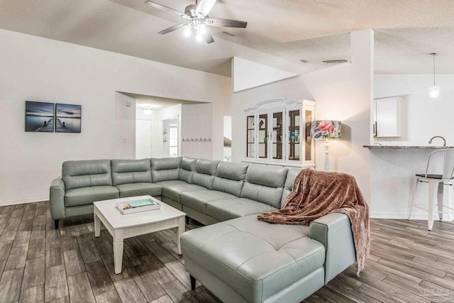 living room with a textured ceiling, ceiling fan, hardwood / wood-style floors, and lofted ceiling