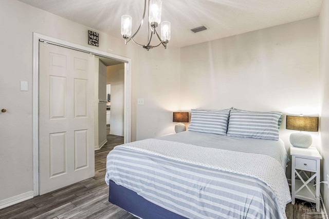 bedroom with dark hardwood / wood-style flooring, an inviting chandelier, a closet, and a barn door