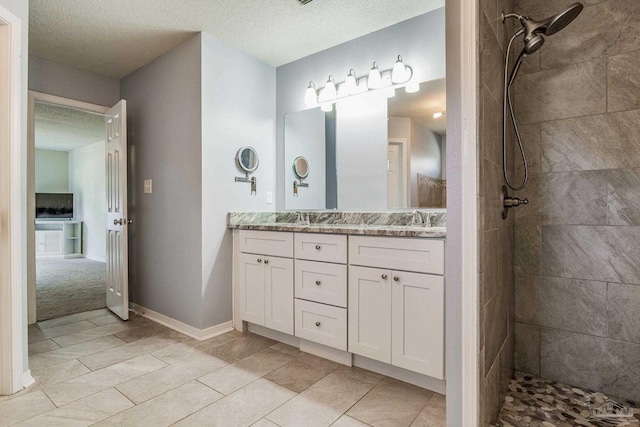 bathroom with vanity, a tile shower, a textured ceiling, and tile patterned floors