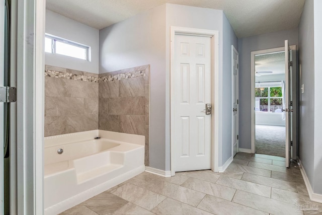 bathroom featuring a textured ceiling, plenty of natural light, and a bathing tub