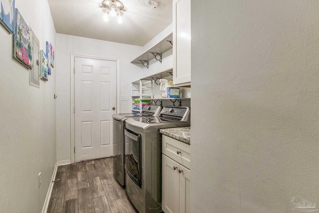 laundry area with a textured ceiling, cabinets, dark wood-type flooring, and washing machine and dryer