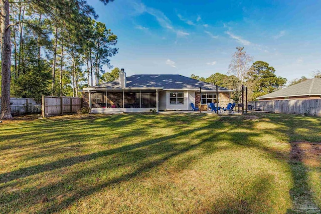 rear view of house with a lawn, a sunroom, and a patio area