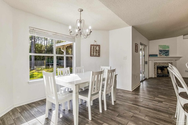 dining space with a high end fireplace, a textured ceiling, vaulted ceiling, dark wood-type flooring, and a chandelier