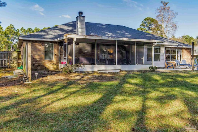 rear view of property with a yard, a patio area, and a sunroom