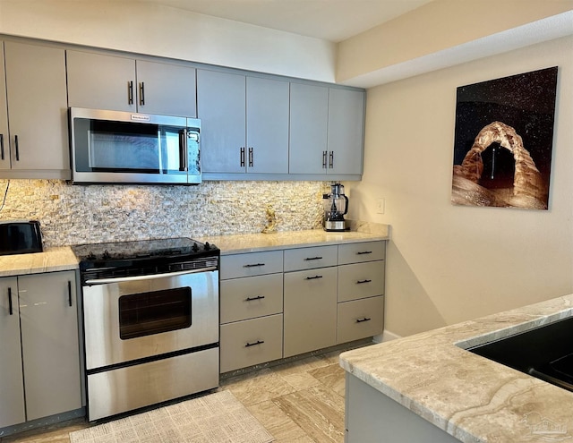 kitchen with stainless steel appliances, backsplash, and gray cabinetry