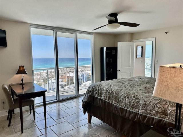 bedroom with baseboards, a water view, access to exterior, floor to ceiling windows, and a view of the beach