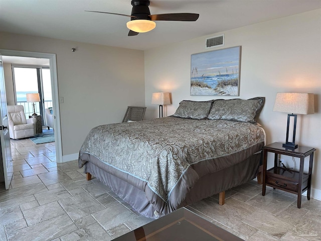 bedroom featuring a ceiling fan, stone tile floors, visible vents, and baseboards