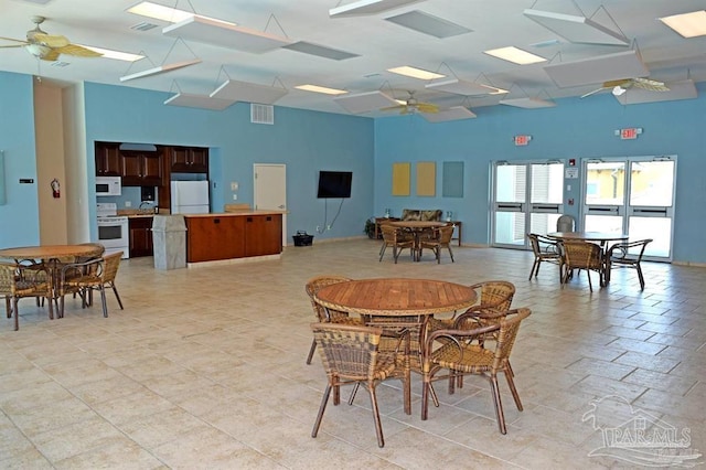 dining room with a ceiling fan, visible vents, and a high ceiling