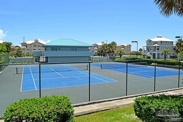 view of tennis court featuring a residential view and fence