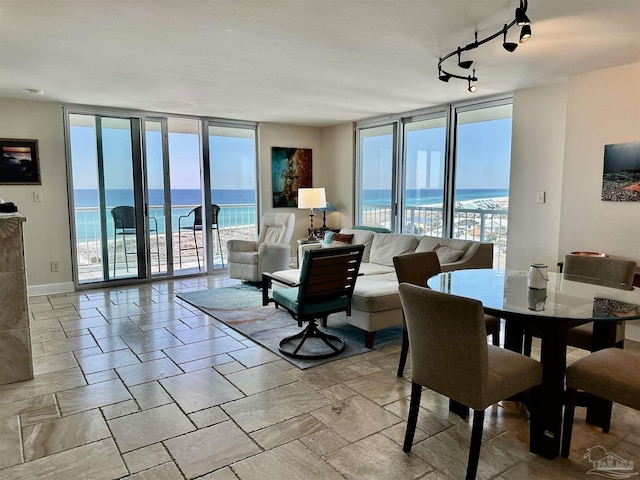 dining space with a water view, expansive windows, baseboards, and track lighting