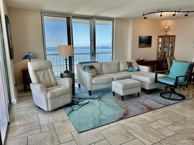 living room featuring a wall of windows, stone tile flooring, and track lighting