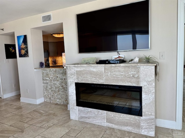 interior details with fridge, visible vents, baseboards, and a glass covered fireplace