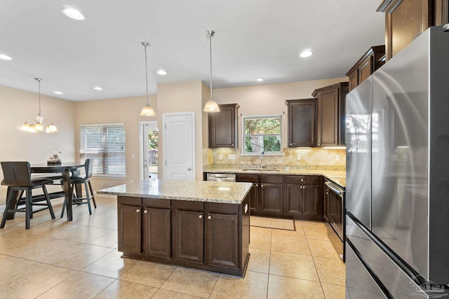 1824 Lindsey Magnolia Ct, Navarre, FL 32566 - kitchen featuring appliances with stainless steel finishes, a sink, backsplash, dark brown cabinets, and light stone countertops