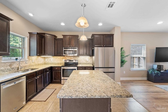 1824 Lindsey Magnolia Ct, Navarre, FL 32566 - kitchen with appliances with stainless steel finishes, a sink, dark brown cabinets, light stone countertops, and recessed lighting