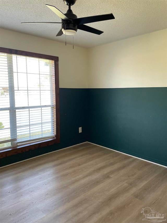 spare room with ceiling fan, wood-type flooring, and a textured ceiling