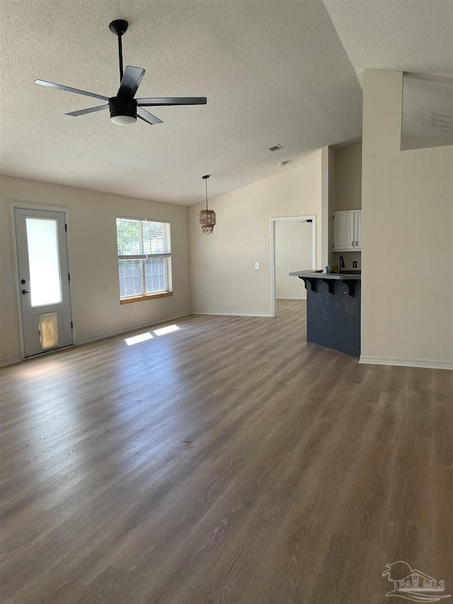 unfurnished living room with lofted ceiling, sink, ceiling fan, dark hardwood / wood-style floors, and a textured ceiling