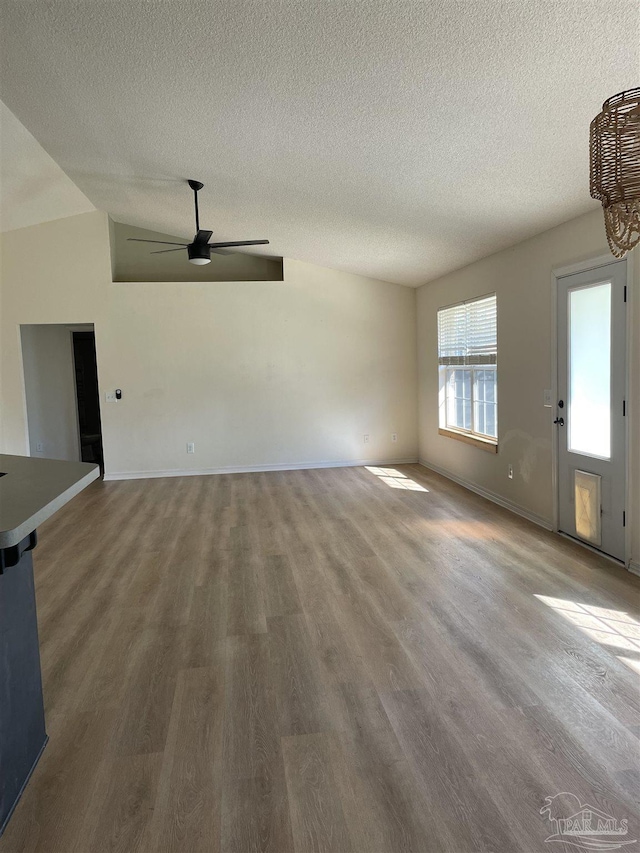 unfurnished living room featuring a textured ceiling, wood-type flooring, ceiling fan, and vaulted ceiling