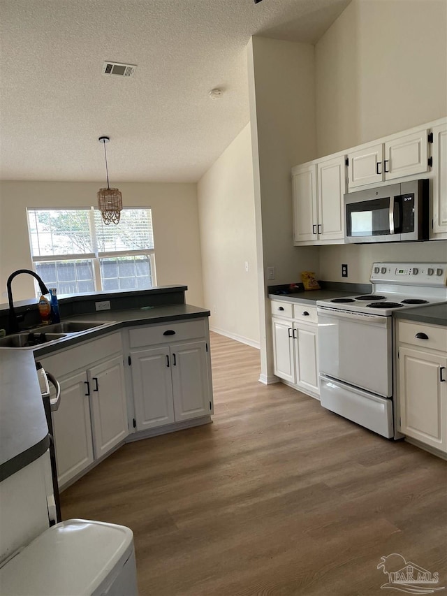 kitchen with sink, white cabinetry, decorative light fixtures, light wood-type flooring, and electric stove