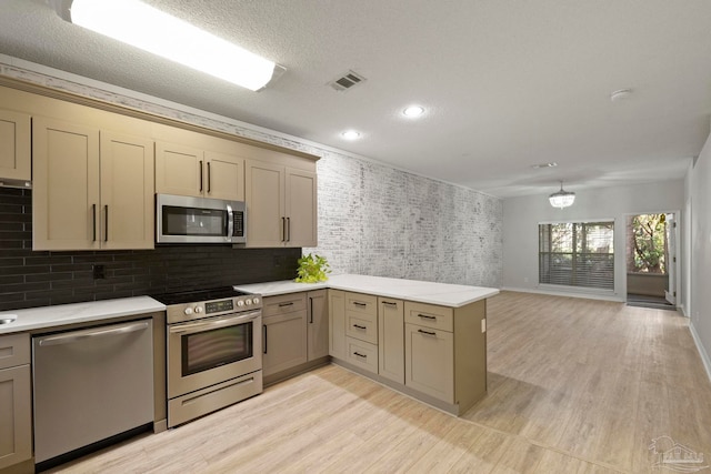 kitchen featuring a textured ceiling, kitchen peninsula, stainless steel appliances, and light hardwood / wood-style flooring